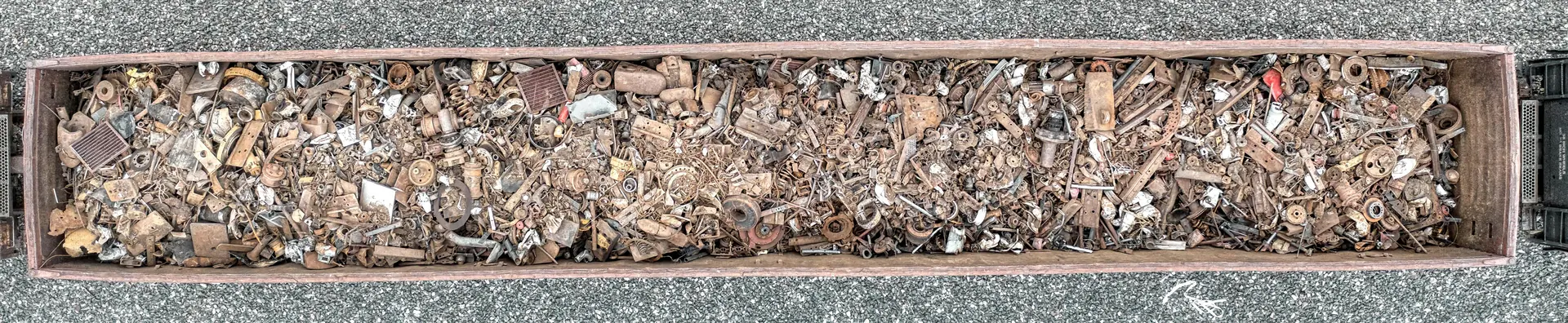 A rail wagon loaded with mixed scrap metal, seen from directly above alongside the track